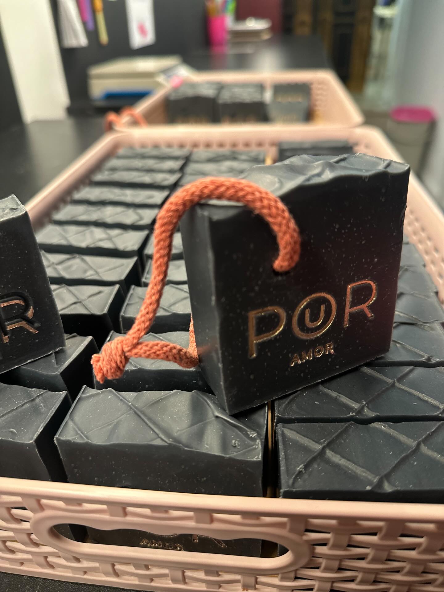 Sabonetes naturais PoUR AMOR pretos numa cesta de produção artesanal